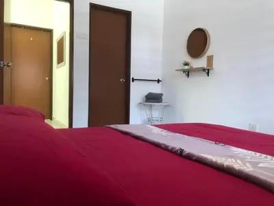 a red bed in a white room with a door at Al Ghazali Homestay in Seri Iskandar