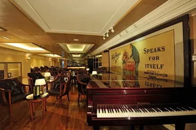 a room with a piano and chairs and a bar at Royale Chulan Penang in George Town