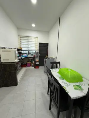 a kitchen with a table with a green pillow on it at Mikhail's Homestay in Sungai Petani