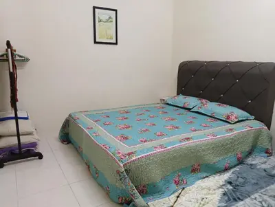 a bed with a quilt on it in a bedroom at Homestay Kak Ninie in Teluk Intan