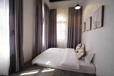 a bedroom with a white bed in front of a window at Ipoh Old Town Heritage Family Suite-6R4B -12-16pax in Ipoh