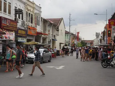 a group of people walking down a busy city street at Inn Residence 18 in George Town
