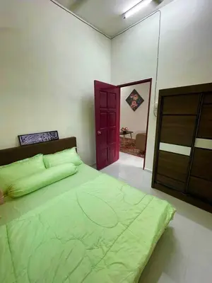 a bedroom with a green bed and a red door at Tok Abah Homestay Bukit Mertajam in Bukit Mertajam