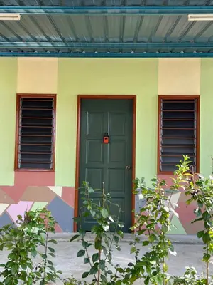 a green door on a colorful building with two windows at Slim Village Palm House - 2 rooms, 8 beds, 8 persons in Slim River