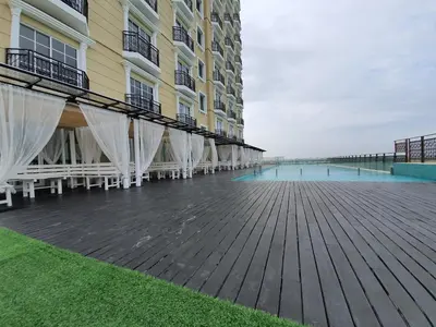 a building with a wooden deck and a building with white curtains at NICE and COZY studio apartment with gym and pool. in Kampar