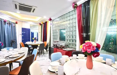 a restaurant with tables and chairs and a vase of flowers at Penang Dream Banglo Sleeps 65 in Tanjung Bungah