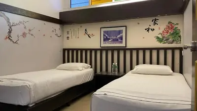 two beds in a room with chinese writing on the wall at GOPENG INN in Gopeng