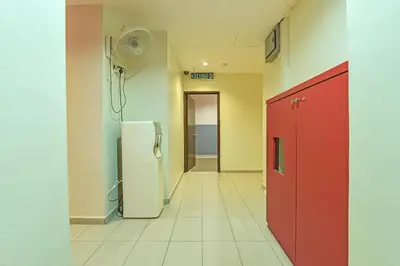 an empty hallway with a refrigerator and a red door at Hotel O M Three Hotel in Kampong Batu Tiga