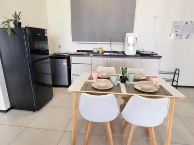 a kitchen with a table with white chairs and a table at Cozy Minimalist Suite at Urban Suites Georgetown by SuperStay in Jelutong
