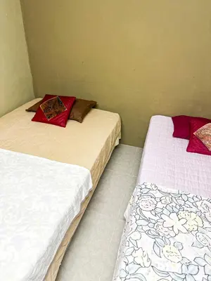 two beds sitting next to each other in a room at Dusun Indah Cottage 3 in Bayan Lepas