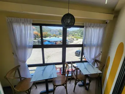 a dining room with two tables and a large window at Clock Inn Backpackers Hostel in Tanah Rata