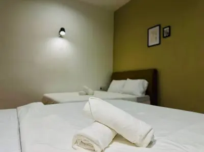 a hotel room with two beds and a towel on the bed at (New) Beachside Antique Villa@14 pax in George Town