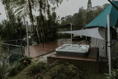 a hot tub sitting on a deck with an umbrella at Safari Tent with Private Jacuzzi in Brinchang
