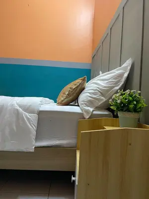 a bedroom with a bed with pillows and a cabinet at Venice Raudhah Guest House in Lumut