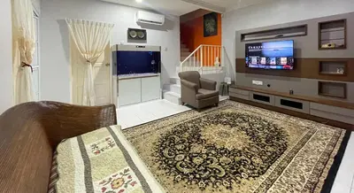 a living room with a tv and a couch and a chair at Venice Raudhah Guest House in Lumut
