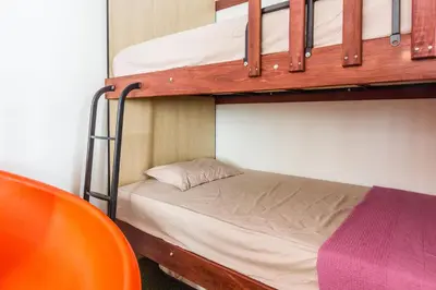 a bedroom with two bunk beds and a orange chair at Varnen Cozy Haven - EVCharger in Bukit Mertajam