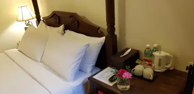 a hotel room with a bed with white pillows and a night stand with at Betel Nut Lodge in George Town