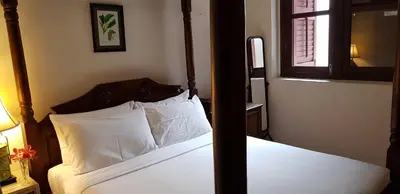 two pictures of a bedroom with a bed and a window at Betel Nut Lodge in George Town