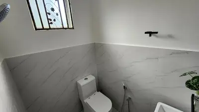 a white bathroom with a toilet and a window at Villa Fatima in Sitiawan