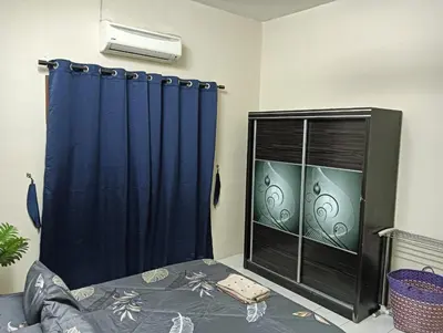 a bedroom with a blue curtain and a window at Homestay Itqan Seri Iskandar in Seri Iskandar