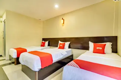 two beds in a hotel room with red pillows at OYO 89960 Manjung Inn Hotel in Seri Manjung