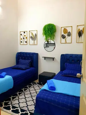 a bedroom with two beds and a blue couch at LH Alisha Homestay Bandar Utama Gua Musang in Gua Musang