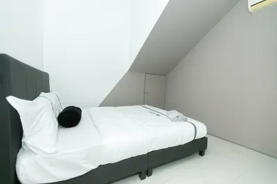 a bed with white sheets and a black pillow at Beach side spacious 5BR 20pax pool house in Batu Ferringhi