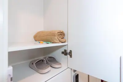 a room with white cabinets with a towel and slippers at Momostay in George Town