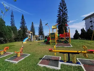 a playground with colorful equipment in a grass field at Little England B8-3 in Bukit Fraser