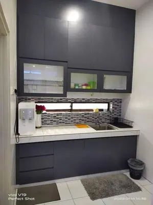 a kitchen with black cabinets and a sink at Homestay Mewah Lumut in Lumut