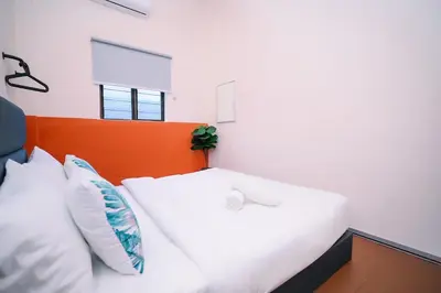 a white bed with an orange headboard and pillows at Swing & Pillows - 75 Chulia St, Georgetown Penang in George Town