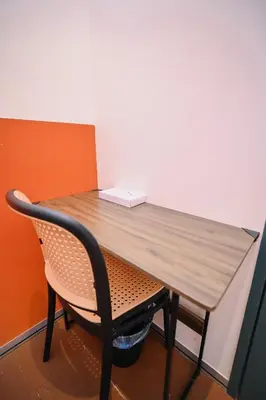 a wooden table with a chair next to a wall at Swing & Pillows - 75 Chulia St, Georgetown Penang in George Town