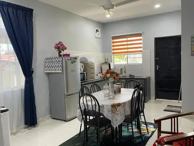a kitchen with a table with chairs and a refrigerator at Homestay Warisan Abang Tam in Kepala Batas