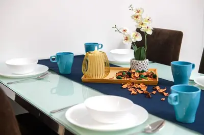 a table with white plates and blue cups and flowers at Deluxe Studio/Gurney/Mansion One in George Town