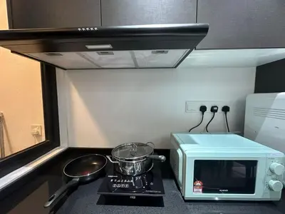 a small kitchen with a microwave and a stove at 3 Room/3 Queen Bed, Urban Suite Arcade Room #2carpark in Jelutong