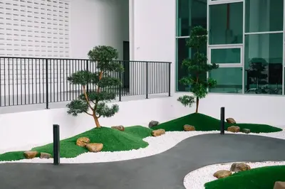a courtyard with two trees and grass in front of a building at Home Cinema - BM City Centre - 4km to Icon City at The Metropol Muji Style Apartment in Bukit Mertajam