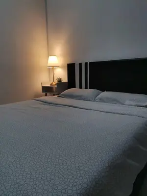 a bedroom with a bed and a lamp on a table at Muji Style brick themed Cameron Highland Homestay FREE Netflix in Tanah Rata