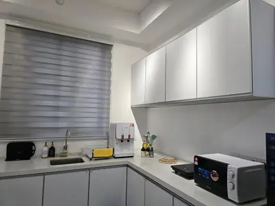 a kitchen with white cabinets and a window with a microwave at Vanilla Cottage - Urban Suites by Ocean Luxe in Jelutong
