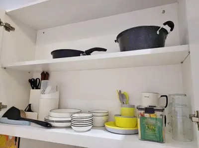 a kitchen shelf with dishes and pots and pans at Sunway Cozy Apartment near Lost World of Tambun in Ipoh