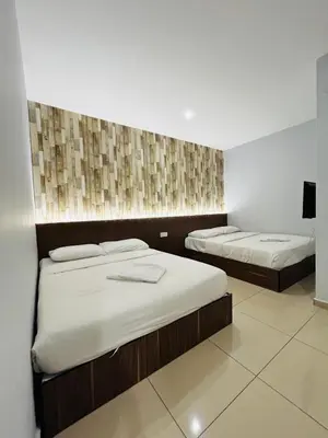 a room with two beds and a tv on a wall at DS Hotel in Ipoh