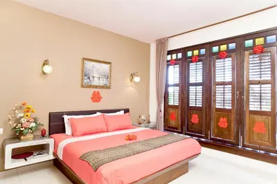 a bedroom with a pink bed and some windows at Hotel O Vince Villa in Bukit Mertajam