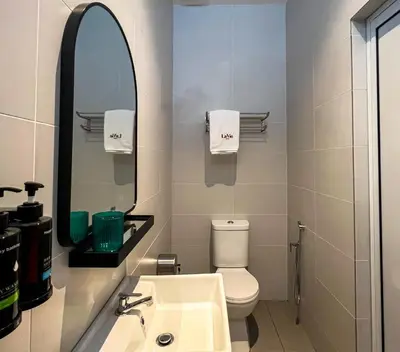 a bathroom with a sink and a mirror and a toilet at La Vie Hotel Juru in Simpang Ampat