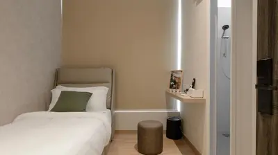 a small bedroom with a bed with a green pillow at La Vie Hotel Juru in Simpang Ampat