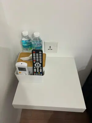 a white shelf with bottles of water and a remote control at KIWI INN in Taiping