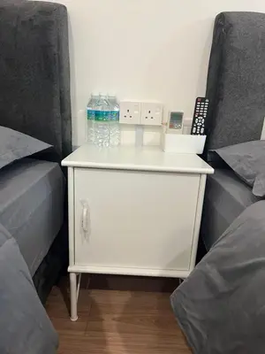 a white dresser with water bottles on it next to two beds at KIWI INN in Taiping