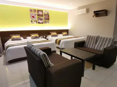 a hotel room with three beds and a table and chairs at Star Bay Hotel in Lumut