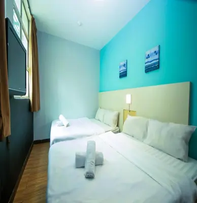 two beds in a room with blue walls at JQ Station Eight Inn in Ipoh