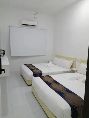 two beds in a hotel room with white walls at SKYN SMART HOME in Ipoh