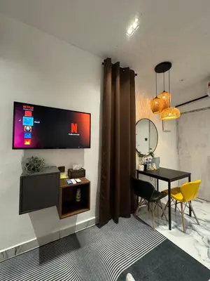 a living room with a table and a tv on the wall at Stylish Balinimo Guest room - King Bed, Free Netflix, Prime & Wi-Fi Near Bukit Mertajam in Kubang Semang