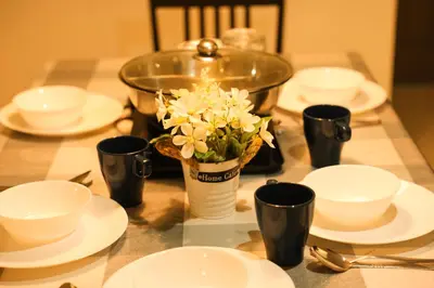 a table with white plates and a vase of flowers at Emerald Avenue Brinchang 8 guests 3 bedrooms in Brinchang